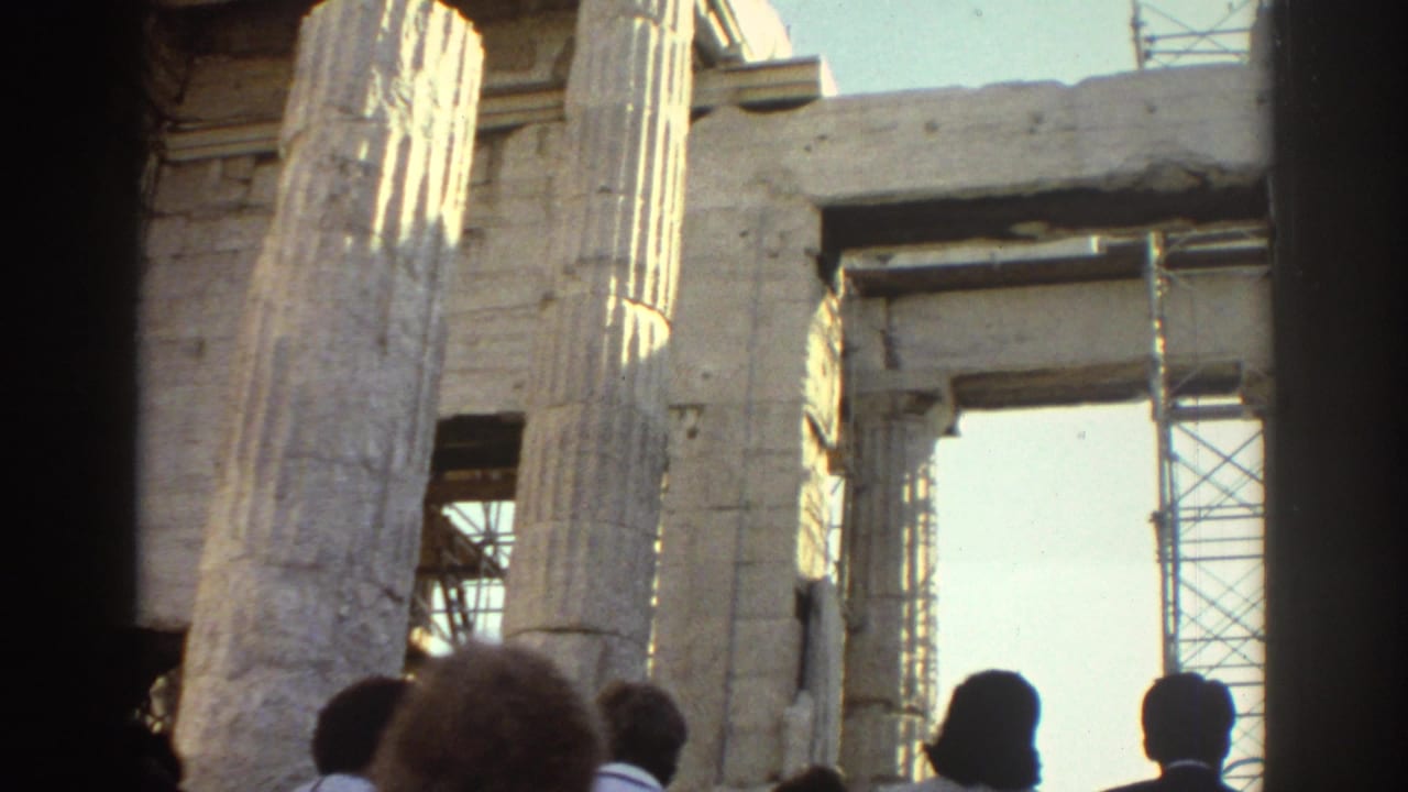 1970s 8mm travel frame showing visitors at the base of fluted stone columns with scaffolding visible through openings.