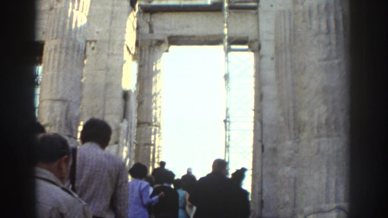 1970s 8mm travel footage shows visitors moving through tall weathered stone ruins with a bright exterior opening ahead.