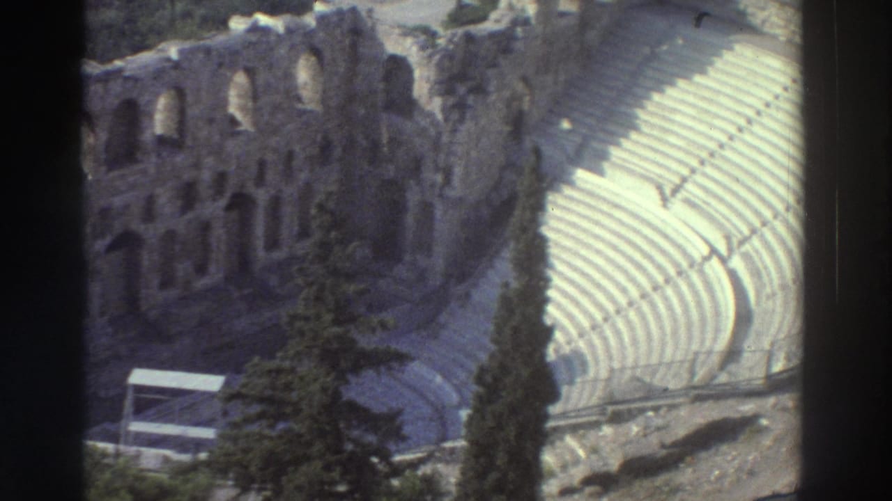 Ancient stone theater seating and ruin wall framed by dark film gate edges.