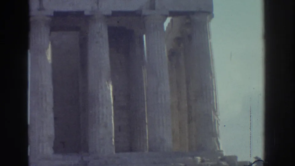 1976 8mm frame from Tel Aviv, Israel, with tall weathered stone columns and entablature details against a pale sky.