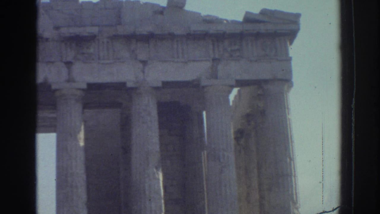 1970s 8mm travel frame showing classical temple columns and broken upper stonework, with dark film edges visible.