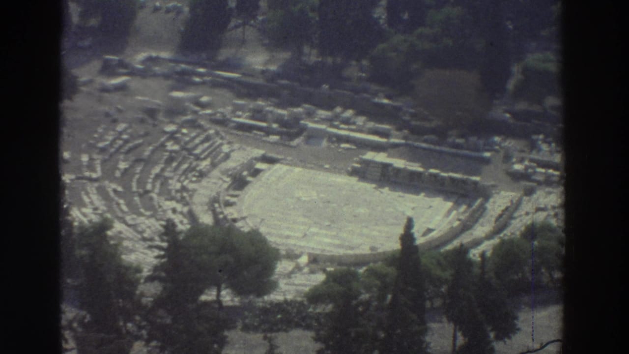 Similar overhead view of the ruin, with stone seating, arena floor, trees, and dark frame edges.