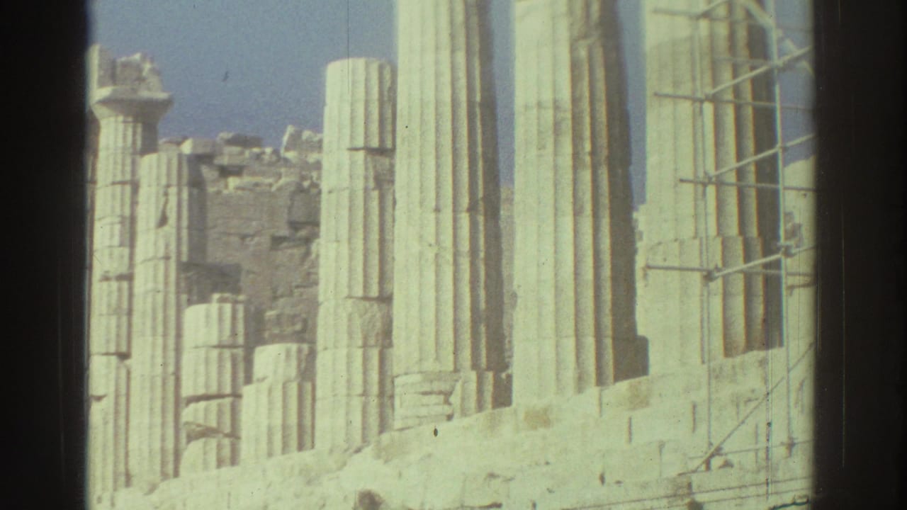 Close view of pale fluted columns, broken stonework and scaffolding at an archaeological site.