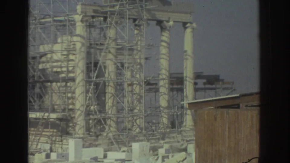 Cataloged 1976 8mm frame showing classical stone columns, dense restoration scaffolding, scattered blocks, and a small wooden structure.