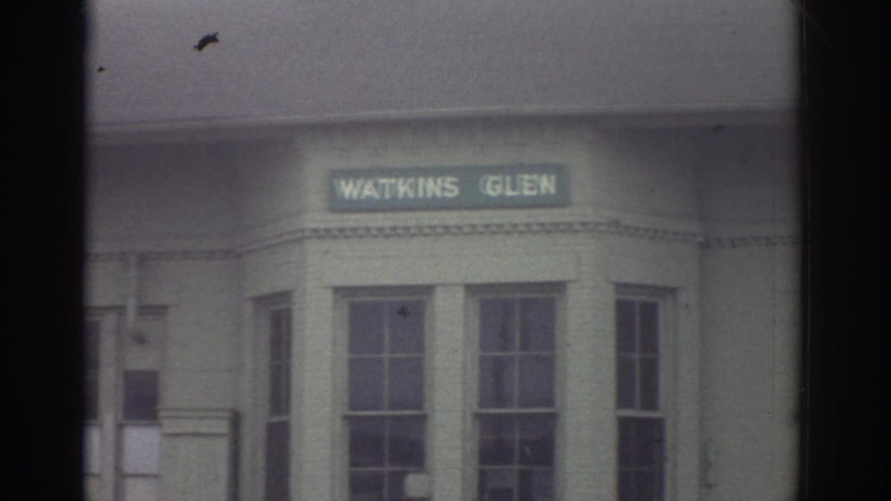 1976 Watkins Glen, New York home-movie frame showing a Watkins Glen sign above windows on a building facade.