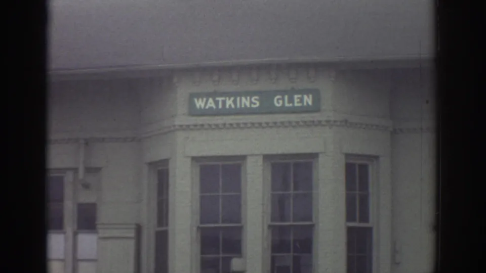 1976 Watkins Glen, New York frame with a close view of a Watkins Glen sign mounted above building windows.