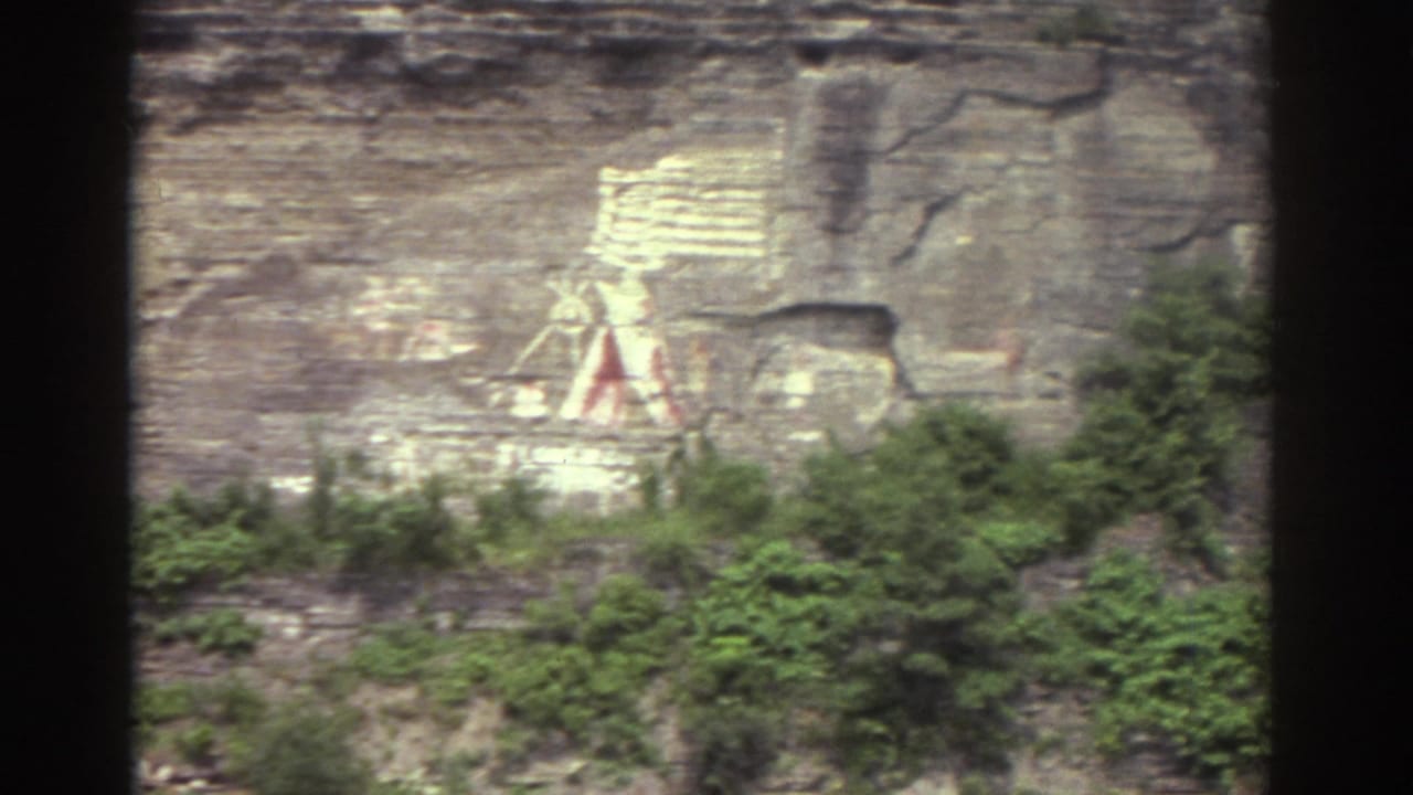 1976 Watkins Glen footage showing a painted cliff mural with a Native American-style figure, teepee form, rock layers, and green brush below.