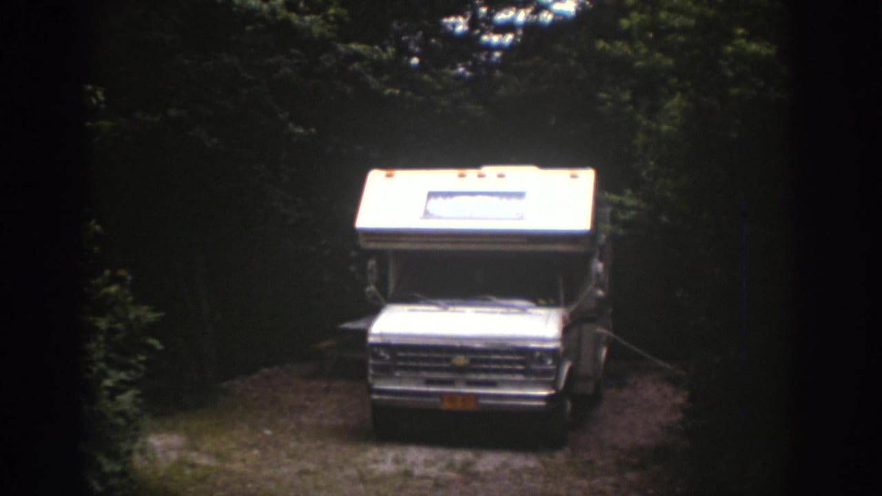 White Chevrolet-front RV sits in a wooded Watkins Glen campsite, filmed from a distance on 8mm stock.