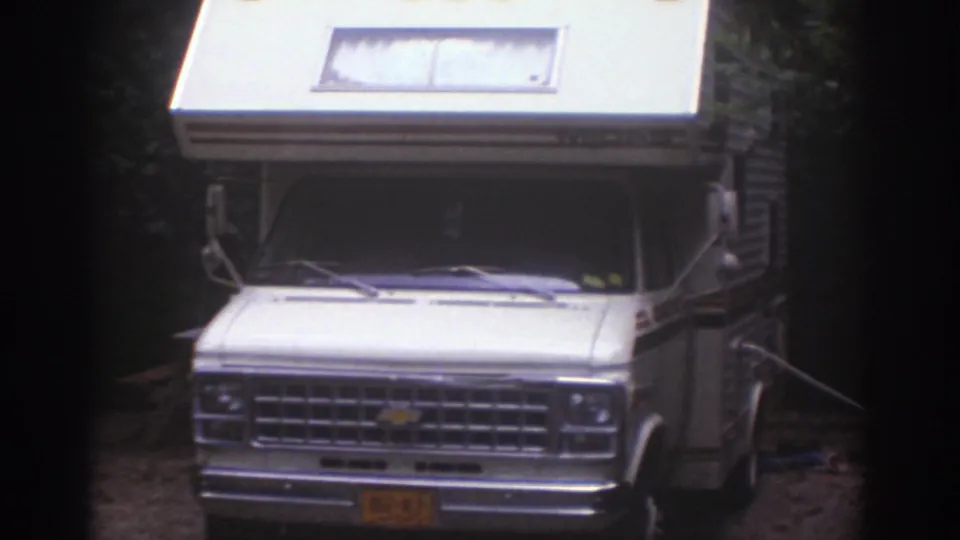 Closer 8mm frame of the white Chevrolet motorhome front at the wooded Watkins Glen campsite.