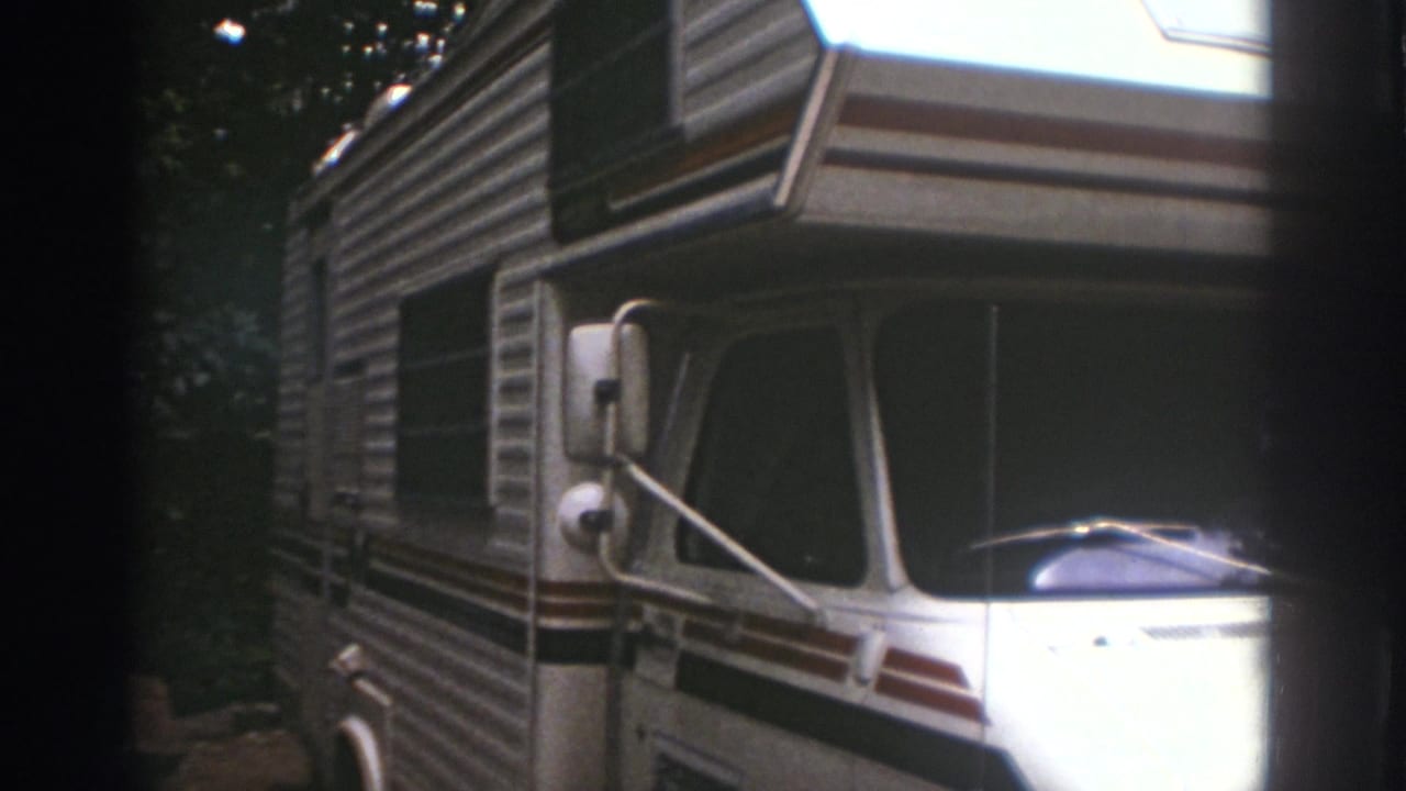 Closer view of the motorhome front and side under trees.