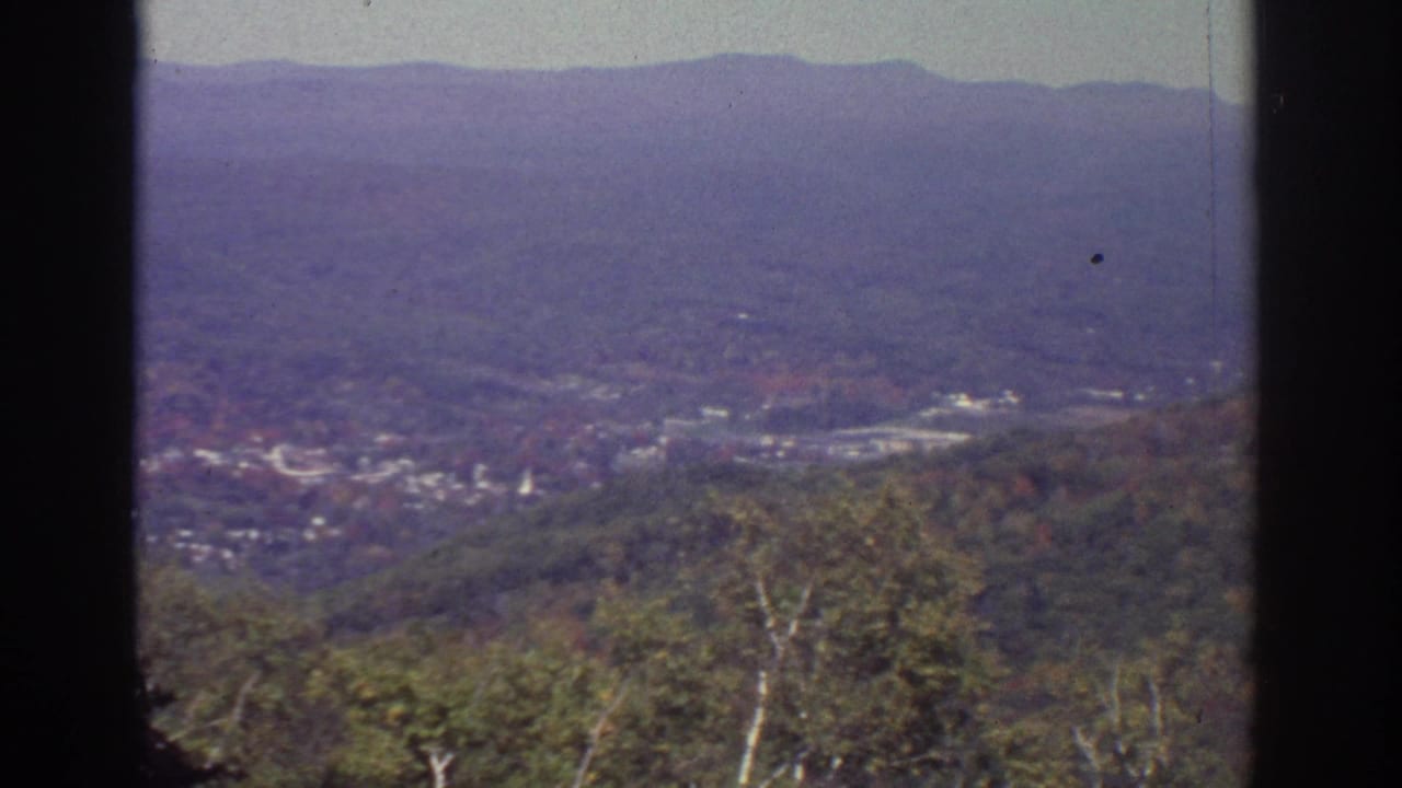 Wide valley panorama with wooded hills, distant ridge, and dark frame edges.