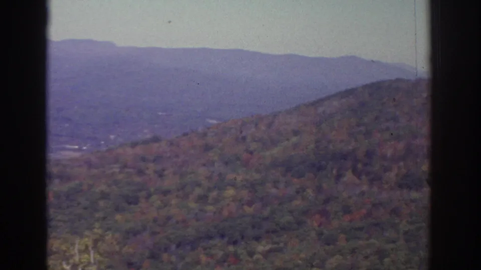 The pan ends on a rolling wooded hillside near Watkins Glen, with muted autumn color, hazy ridge lines, and soft 8mm film texture.