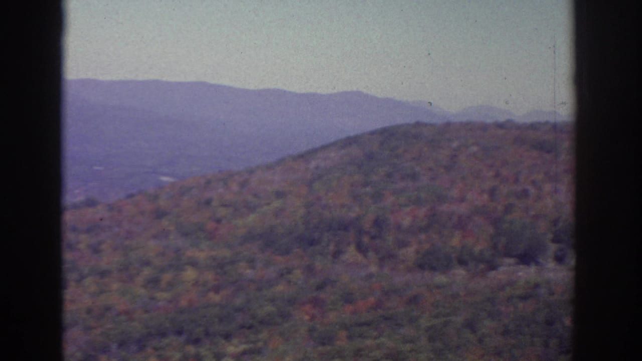 1976 Watkins Glen-area 8mm view of autumn hills, distant mountains, pale sky, and dark film-gate borders.