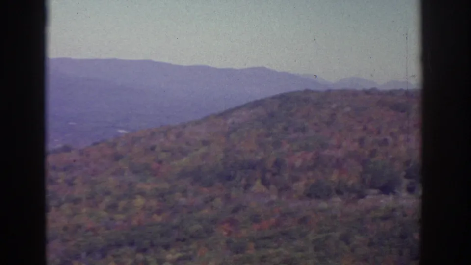 1976 Watkins Glen-area 8mm view of autumn hills, distant mountains, pale sky, and dark film-gate borders.