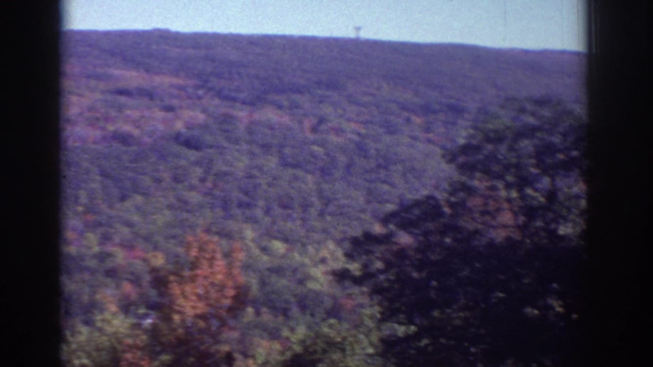 Distant forested ridge with autumn color and dark borders at the sides.