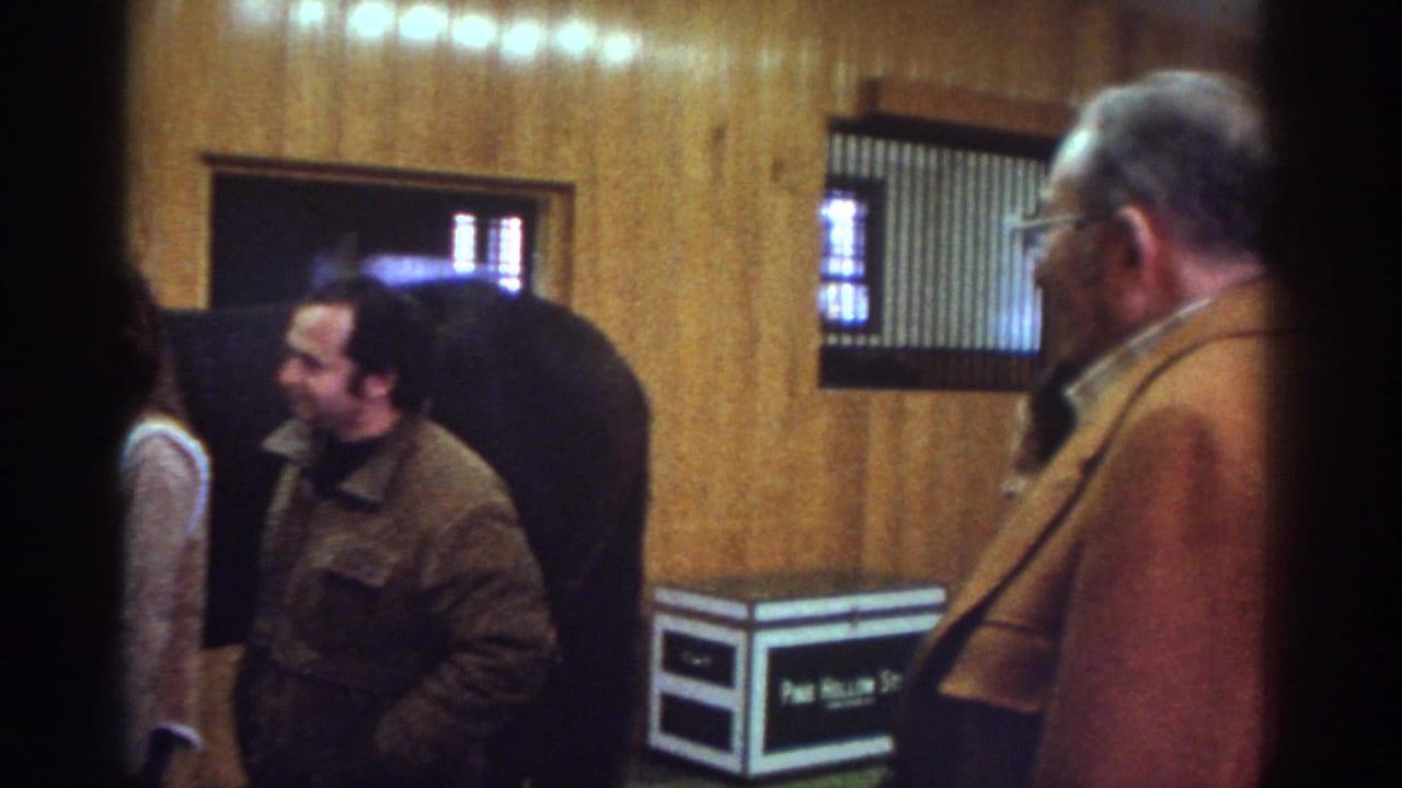 1976 Watkins Glen stable interior with adults standing near a dark horse and a second man visible at the right edge.