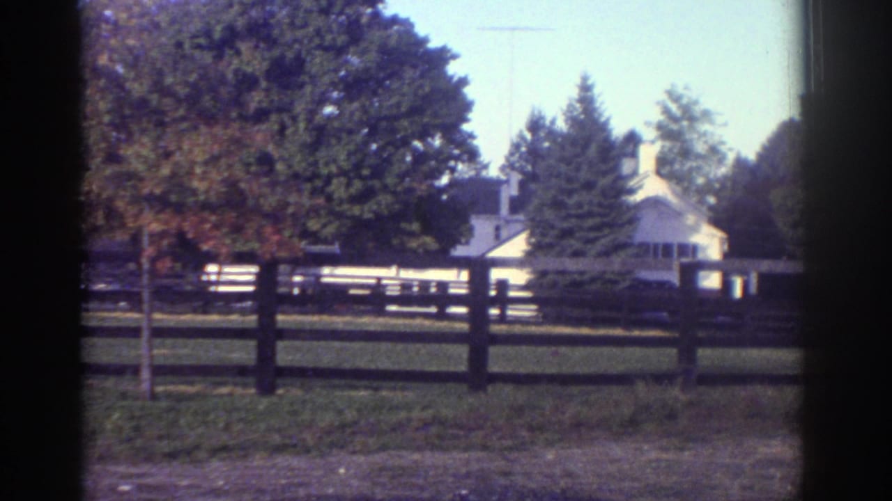 1976 Watkins Glen rural property view with a white house, rail fence, lawn, and large trees.
