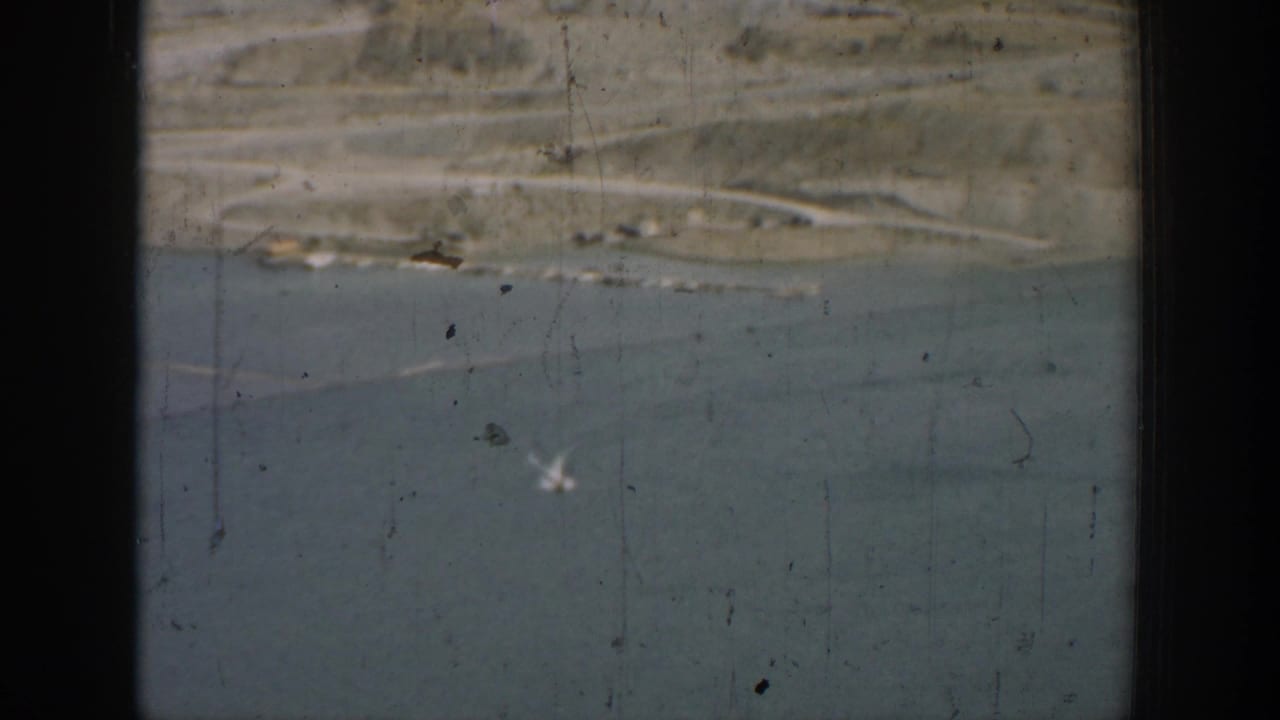 1937 California 8mm frame showing an artificial lake, dry hillside terrain, and a distant shoreline road.