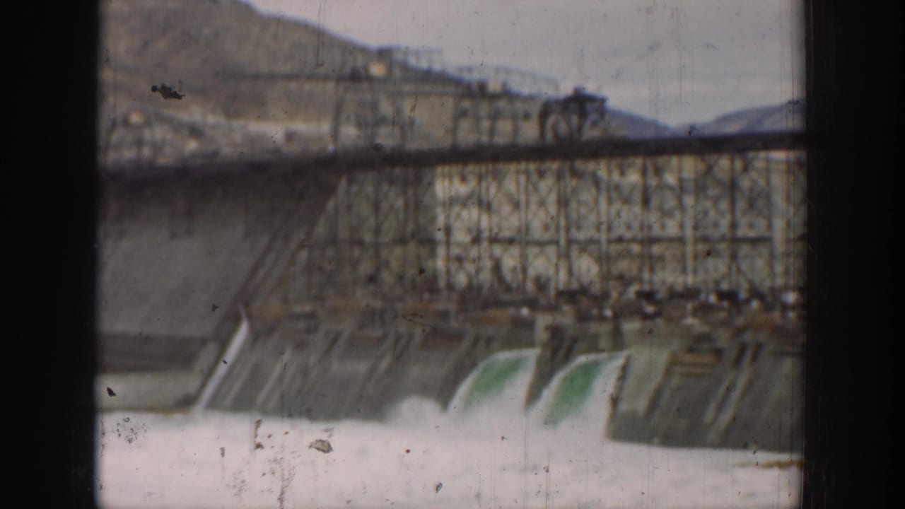 Large California dam works with spillway water and a steel trestle structure, seen in soft 8mm color.