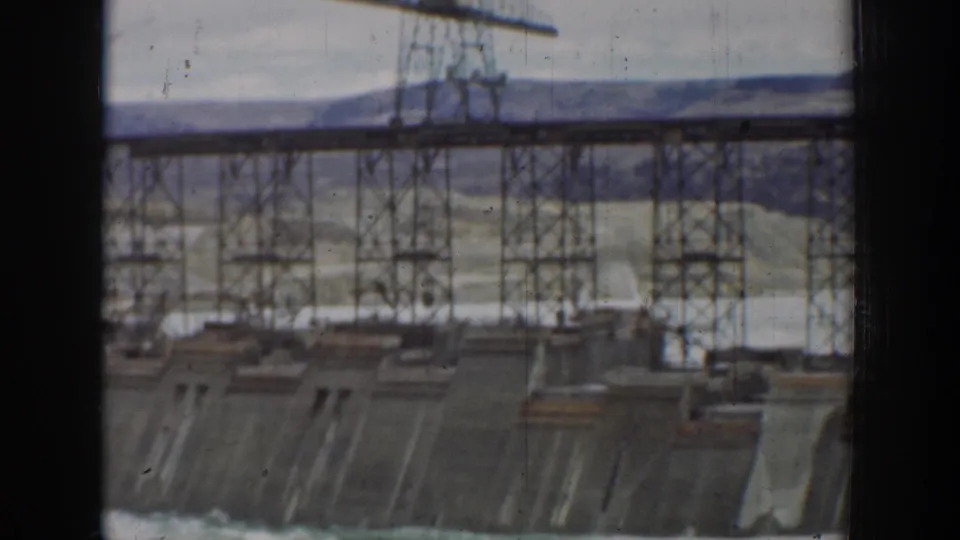 1930s 8mm view of a steel trestle over a concrete dam face at a California construction site.