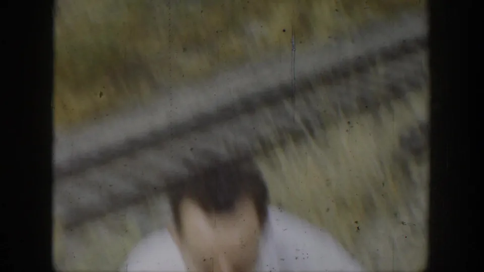 Soft 1937 California 8mm frame with a blurred person close to the camera and a dry outdoor landscape seen through dark framing.