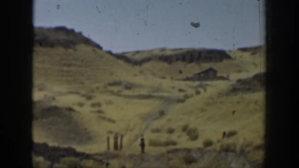 Wide 1937 California 8mm view of dry hills, a winding dirt path, fence posts, and a small distant structure under a pale sky.
