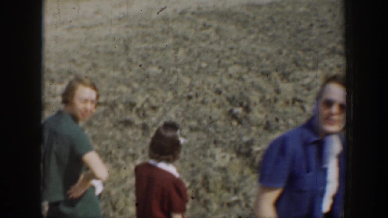 Adults standing near a gravelly slope, with one person looking toward the camera.