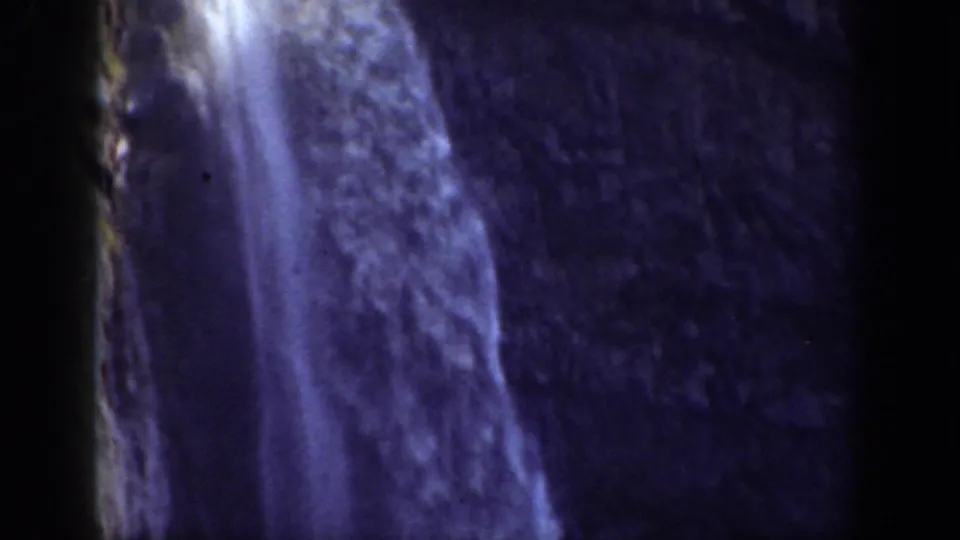 1937 California frame focused on a narrow waterfall cascading down a shadowed rock face.