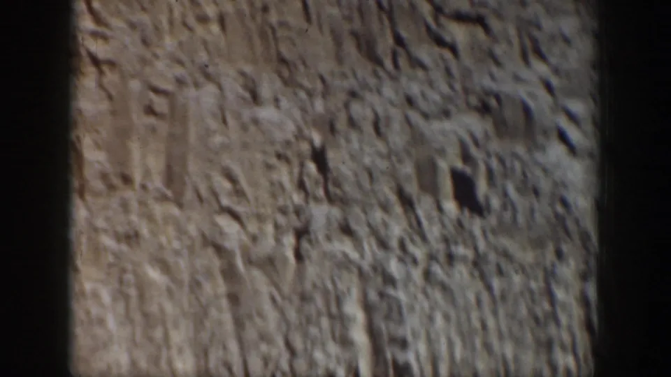 Close-up home-movie view of rugged gray rock surface, likely filmed as a landscape detail near the waterfront.