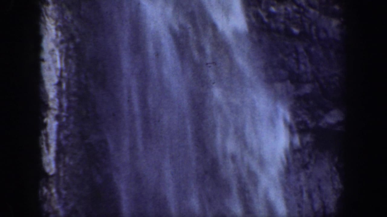 Close view of water falling over a dark rocky surface.