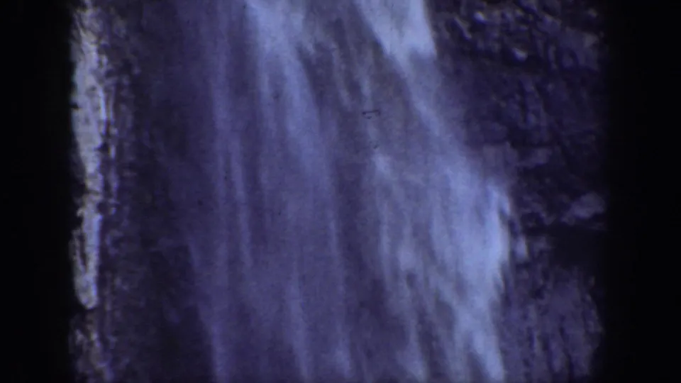 1930s California 8mm frame showing a close view of cascading waterfall water against dark rock.