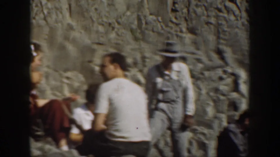 1930s California 8mm frame showing adults gathered on rocks with the waterfall visible behind them.