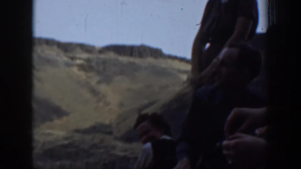 1937 California home-movie frame of shadowed observers at a scenic overlook above hills and sky.