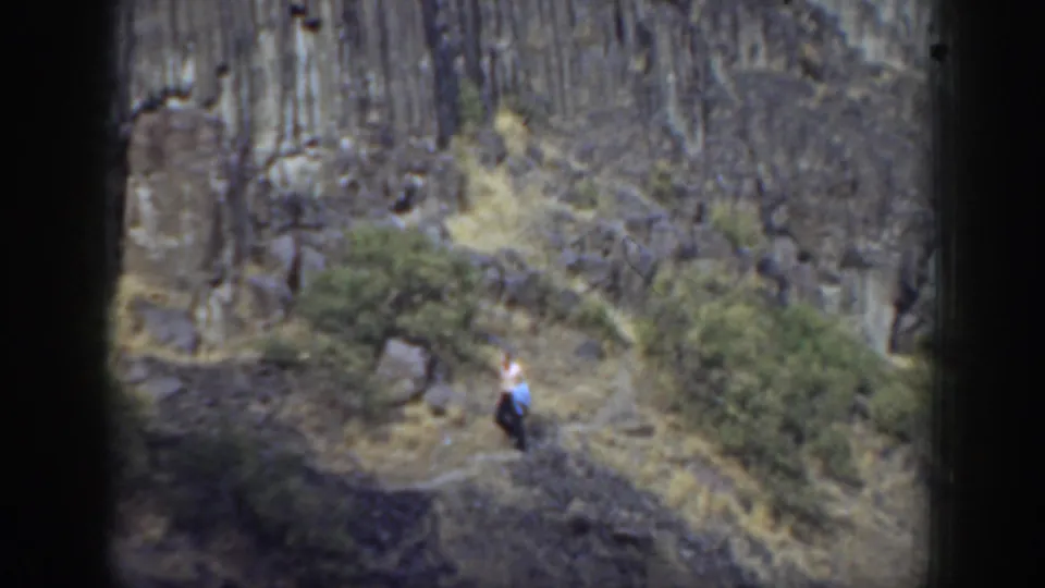 1937 California 8mm still showing a lone figure descending a narrow trail through dry vegetation and rugged rock scenery.