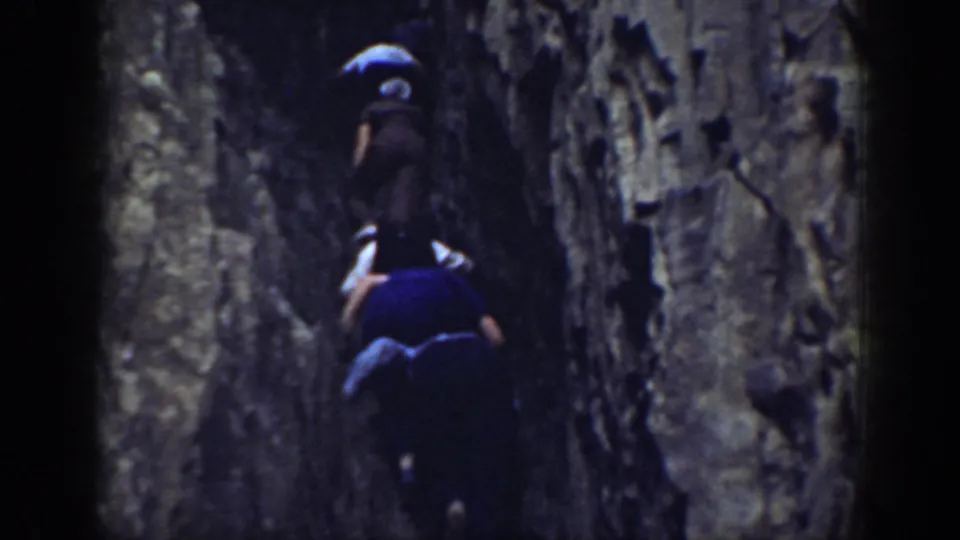 1937 California 8mm frame showing a group ascending a tight rocky crevice, viewed from behind.