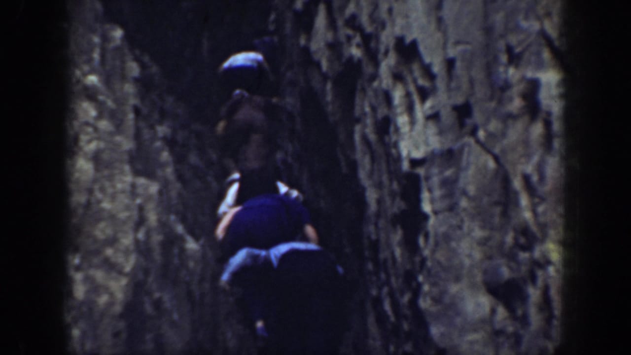 In metadata-supported 1937 California footage, two people move upward between close, rugged rock walls.