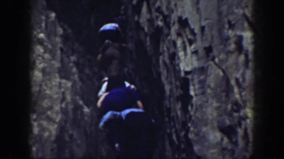 In metadata-supported 1937 California footage, two people move upward between close, rugged rock walls.