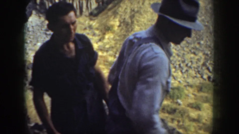 Two adults appear near the exit of the rocky passage, with sunlit ground behind them in the California outdoor setting.