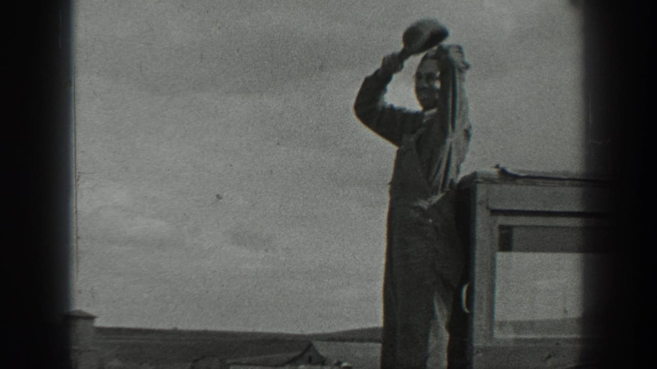 1937 California 8mm frame showing a man in overalls on a raised exterior surface, holding a hat near his face as he looks outward.