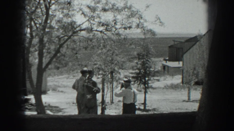 Three men in 1937 California stand beside young trees on a rural property, with a barn-like building and distant fields behind them.