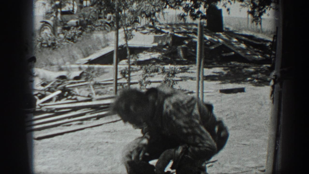 A person bends near scattered lumber and debris outside a structure.