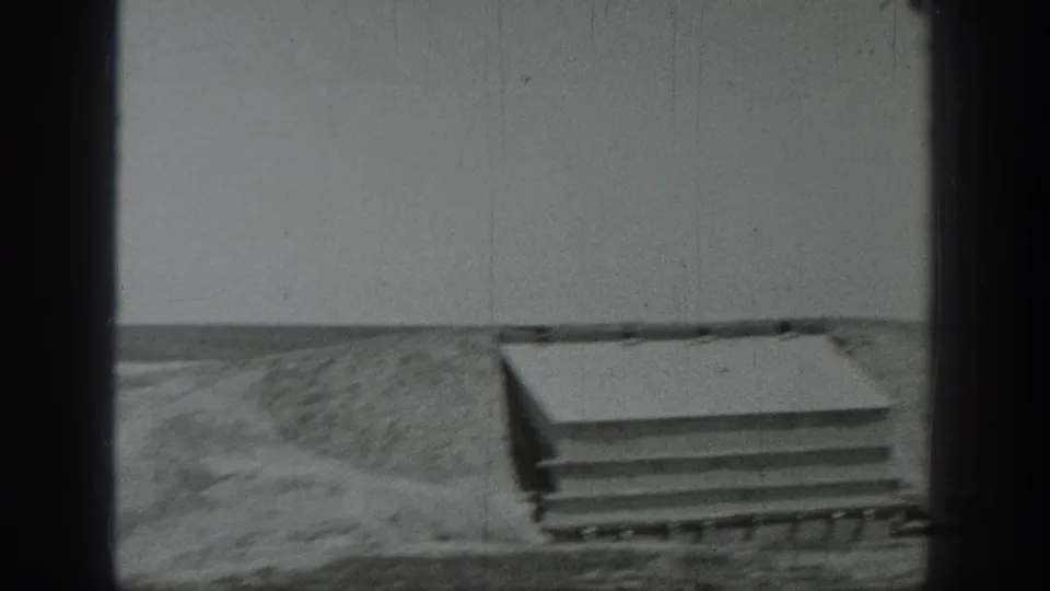 1937 California 8mm frame showing a concrete slab or small platform with steps near open ground and a plain wall.