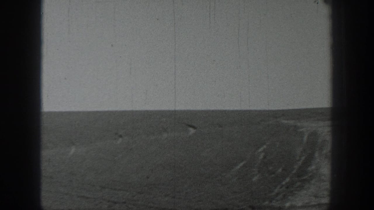 Wide black-and-white horizon over dark open ground beneath a pale sky.