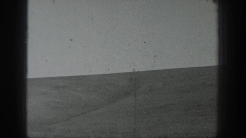 1937 California 8mm frame showing an open agricultural field, low hills, pale sky, and dark film borders during a pan.