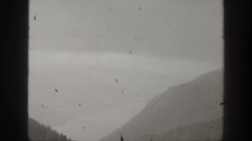 Fog-softened California mountain landscape from 1938 home-movie footage, with evergreen trees low in the frame and visible film wear.