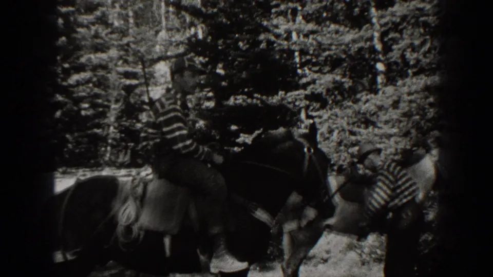 1938 California home-movie frame showing a rider in a striped shirt on horseback among trees.