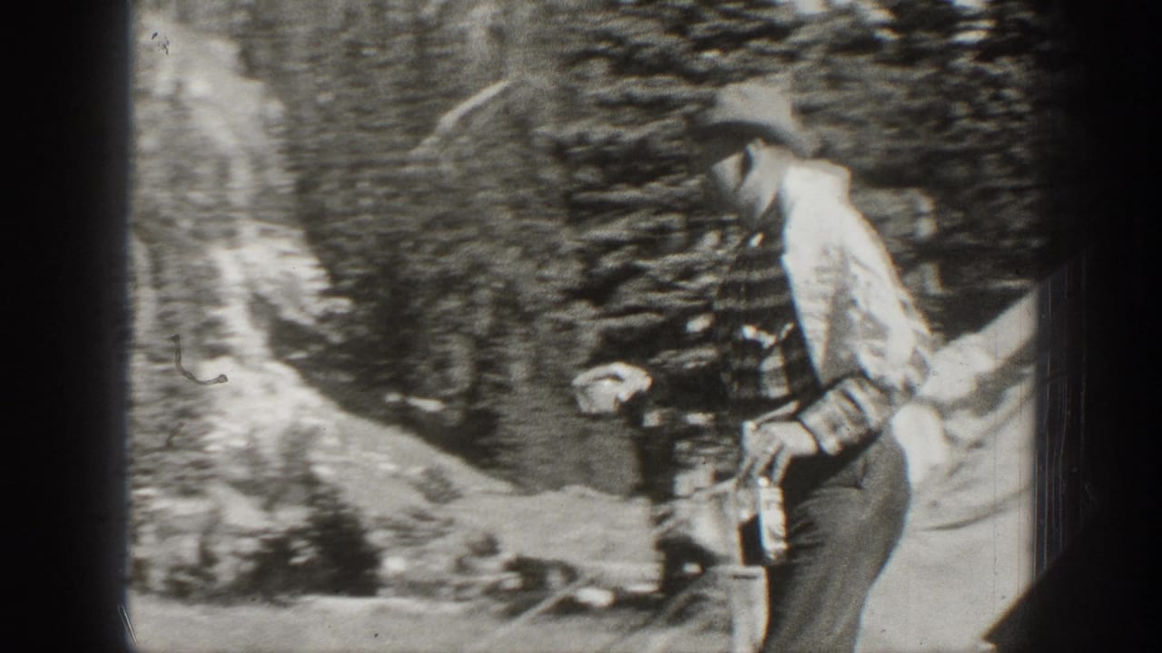 Man in striped shirt and hat carries a bottle through a wooded area.