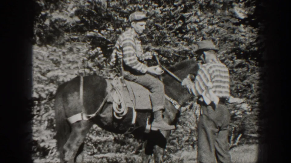 A man on a saddled horse faces another man on foot in a wooded 1938 California outdoor scene.