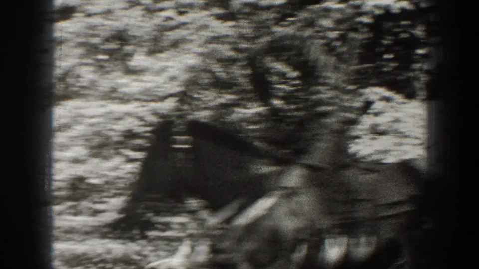 1938 California 8mm frame showing a blurred rider on a saddled horse among trees and rough ground.