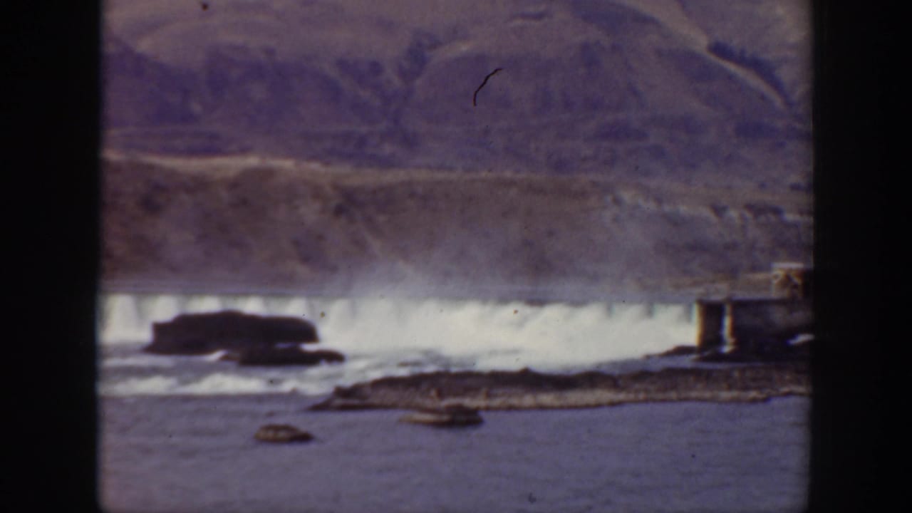 1938 California 8mm frame showing a distant waterfall, river rocks, and a muted mountainside viewed through film gate edges.